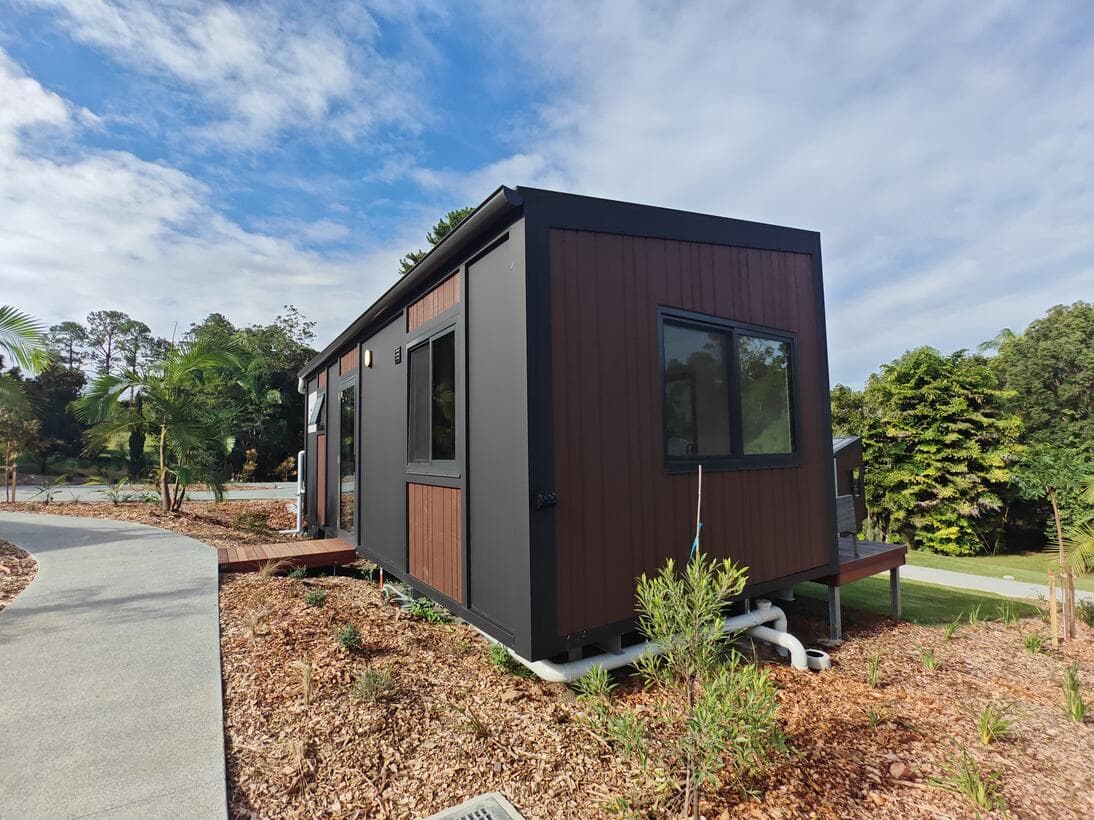 A charcoal and timber AnywhereHomes cabin installed on its block, with a path to the front door