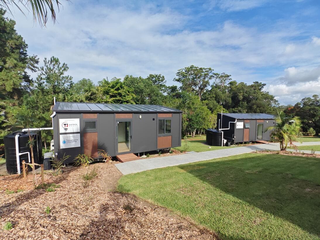 A row of cabins on a single site, sharing a mown lawn